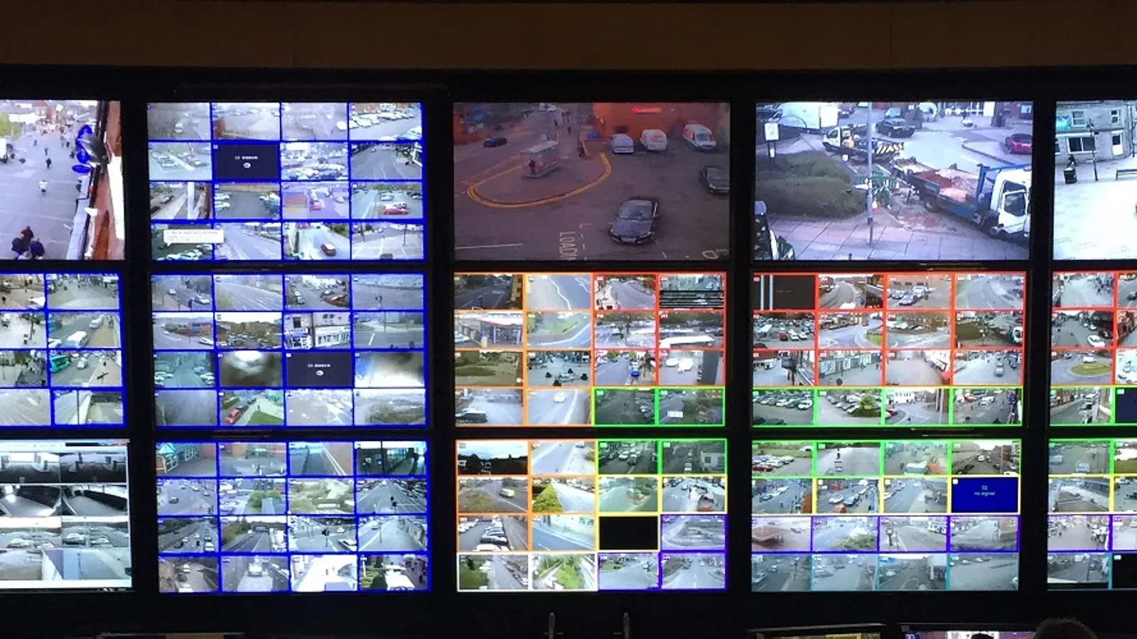 Sala de controle com parede de monitores exibindo múltiplas câmeras de vigilância simultaneamente